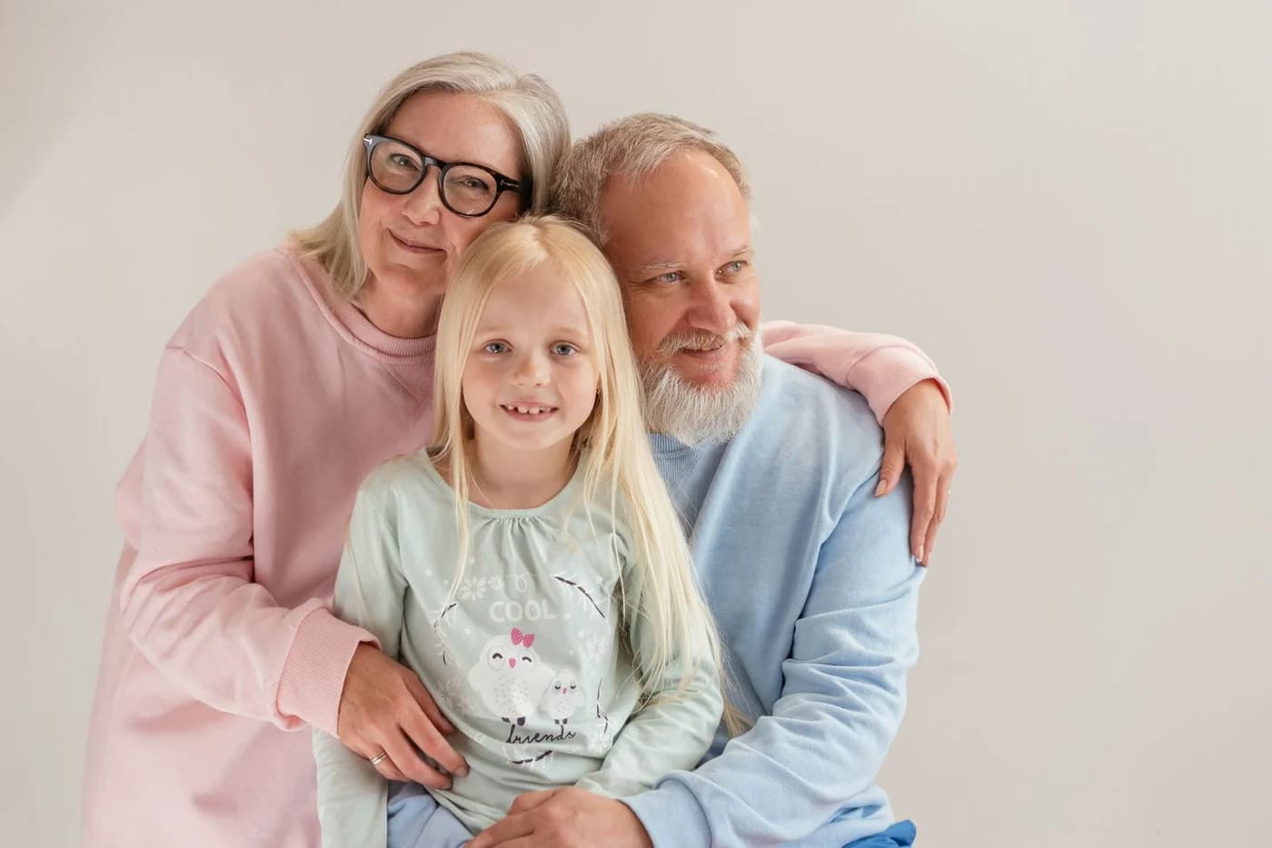 Grandparents embracing their smiling granddaughter